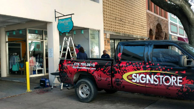 Sign store truck on location in downtown macon installing a sign